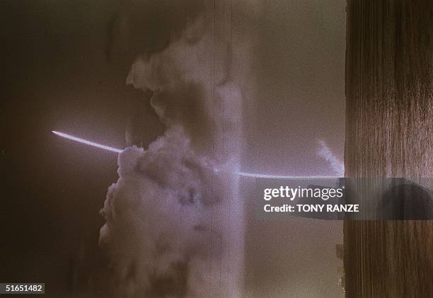 The Titan 4B launch vehicle, carrying the Cassini and Huygens space probes, climbs out of a cloud after blasting off launch pad 40 at Cape Canaveral...