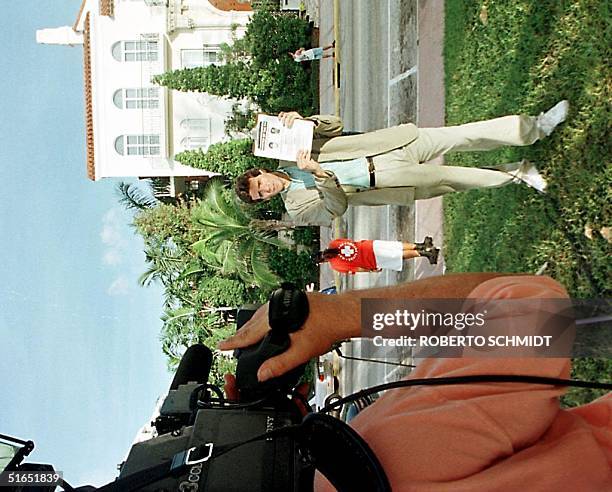 Reporter holds the FBI wanted poster of Andrew Phillip Cunanan in front of the house owned by Italian designer Gianni Versace 16 July in Miami Beach,...