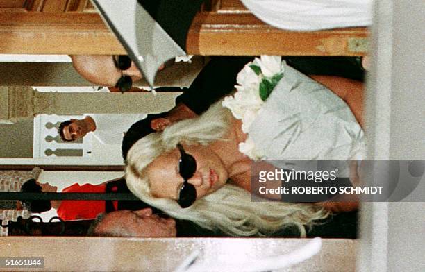 Donatella Versace, the sister of slain Italian designer Gianni Versace, carries some flowers as she leaves her brothers' house through a back door in...