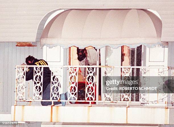 Miami Beach police and FBI agents examine the balcony of a houseboat that was stormed by a police SWAT team on a canal in Miami Beach late 23 July....