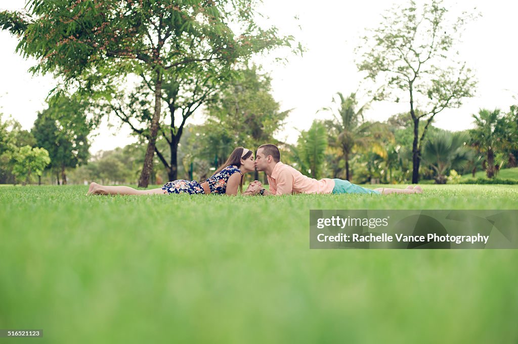 Young couple laying in grass kissing