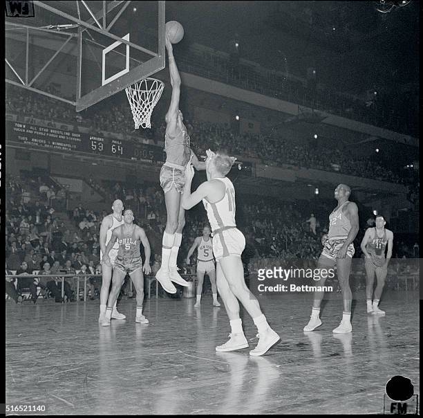 New York, New York: Madison Square Garden. #14 of Knicks Charlie Tyra, and Wilt Chamberlain, in midair recovers rebound.