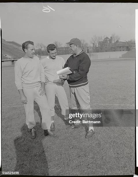 Rams football workout. Bob Waterfield and Norm Van Brocklin check play from backfield coach Hamp Pool, Right.