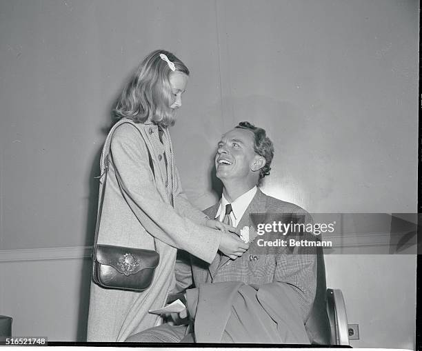 Home from Europe via Scandinavian Airlines out Stockholm, Dr. Peter Lindstrom and daughter Pia are shown at Idlewild Airport. She's fixing a flower...