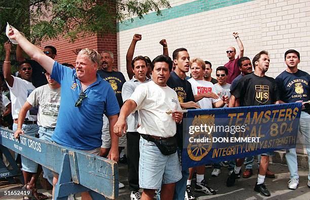 Teamsters at a UPS station in New York wave and cheer as supportive passing motorists honk their horns 19 August. The Teamsters union announced 18...