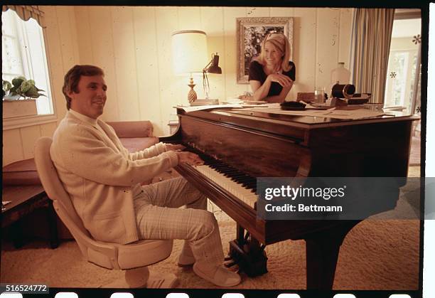 Composer Burt Bacharach plays the piano in his Hollywood home in 1969 while his wife actress Angie Dickinson stands by.