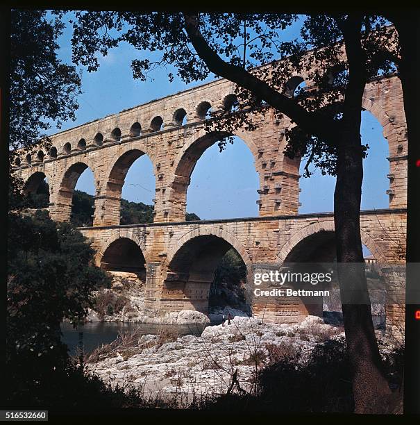 The three tiered Pont du Gard aqueduct spans over the Gard River and green valley, running from Uzes to Nimes, France. | Location: Gard, France.