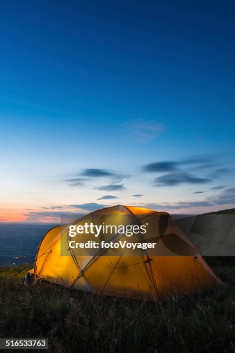 Warmly illuminated dome tent camped on mountain at sunset Warmly illuminated dome tent camped on mountain at sunset