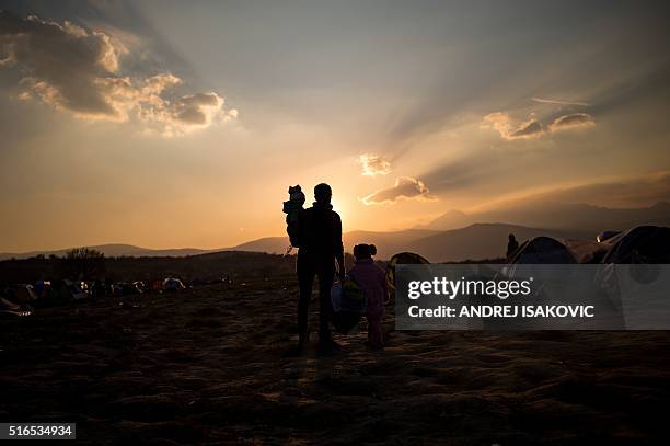 Woman walks with her kids at a makeshift camp near the Greek village of Idomeni at the Greek-Macedonian border where thousands of migrants and...