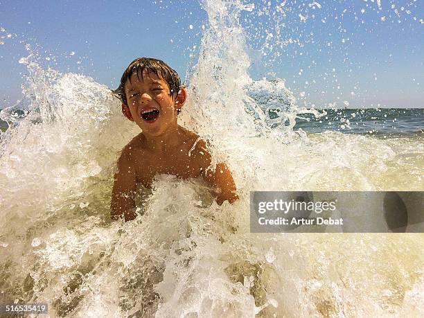 kid get splashed by wave in beach on summertime. - kids splashing stock pictures, royalty-free photos & images