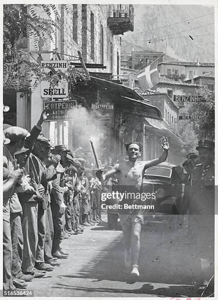 The Olympic torch bearer passes the onlookers triumphantly in Achova on his way to Delphi.