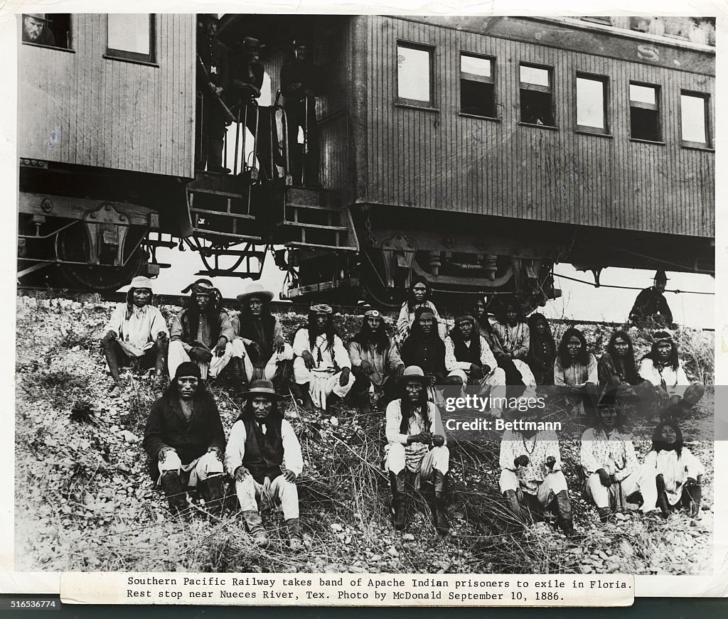 Native Americans Sitting on Embankment Near Train Cars