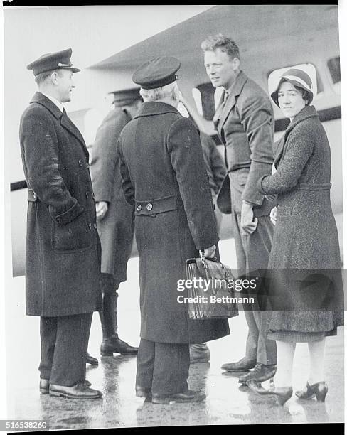 Colonel and Mrs. Charles A. Lindbergh being greeted by two customs officers assigned to expedite their clearance through the airport as they landed...