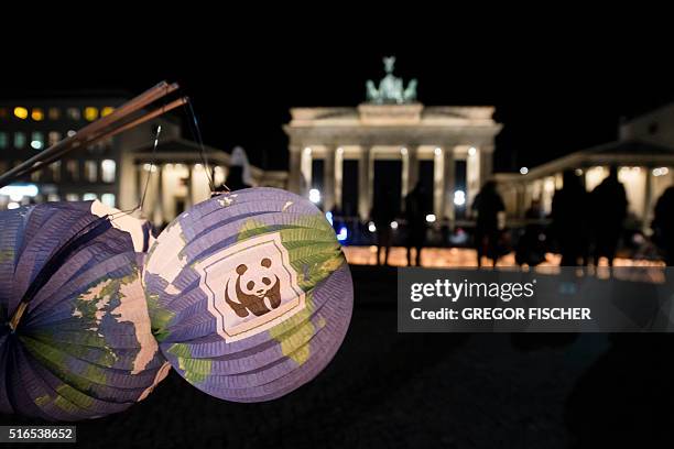 Lanterns with the logo of the World Wildlife Fund are seen during the "Earth Hour" action in front of the Brandenburg Gate in Berlin on March 19,...