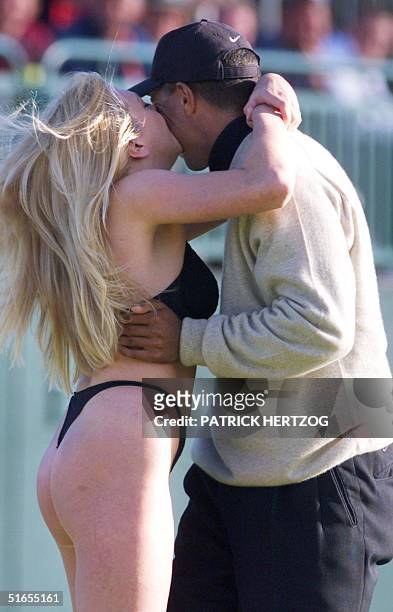 Golfer Tiger Woods gets a kiss from a woman clad in a bathing-suit on the 18th green just before he made his last putt of the day at Carnoustie 15...
