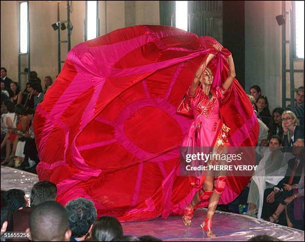 Model presents a crimson dress with kneepads while trailing a billowing parachute-like train by British designer John Galliano for Christian Dior,...