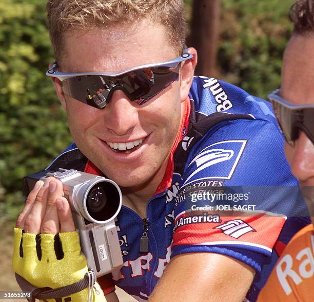 American rider Christian Vandevelde films with a cine-camera one of the cyclists of the pack during the last stage of the 86th Tour de France between...