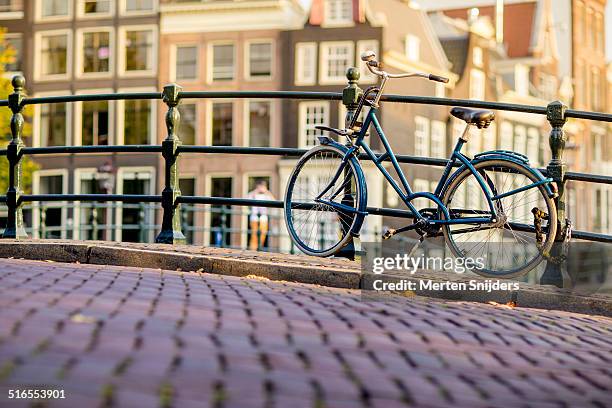 modern bicycle parked against canal bridge - amsterdam bike stockfoto's en -beelden