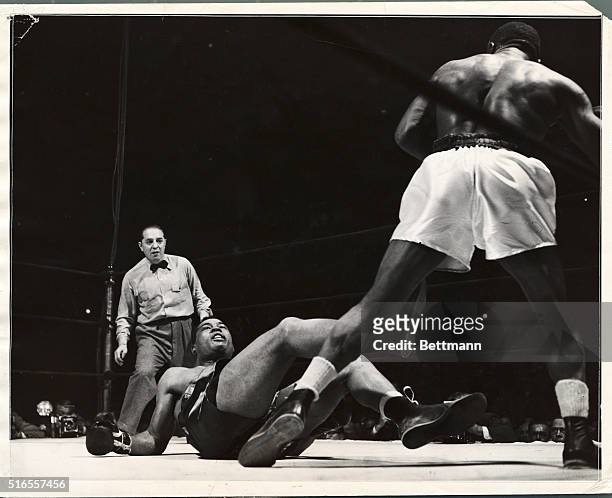 Joe Louis down in the fourth round of his bout with Jersey Joe Walcott. Referee Goldstein looks on from the corner.