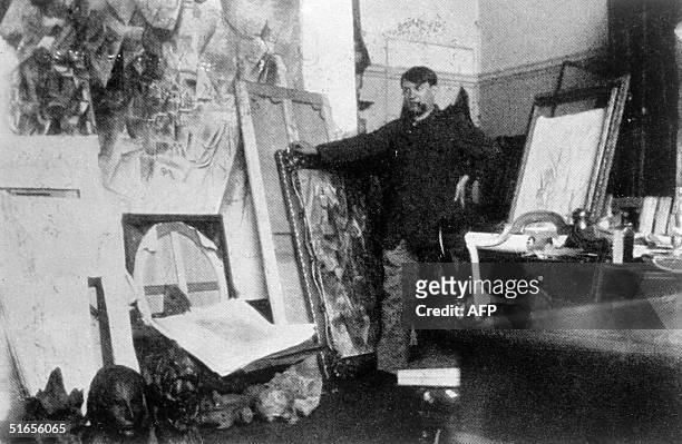 Spanish painter Pablo Picasso poses in the 20th in his Paris' Clichy studio with the largest of his canvases for the field project.