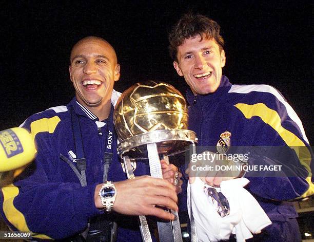 Brazilian Roberto Carlos and teammate Croatian Davor Suker of Real Madrid hold the trophy at their arrival in Madrid 02 December. Real Madrid club...
