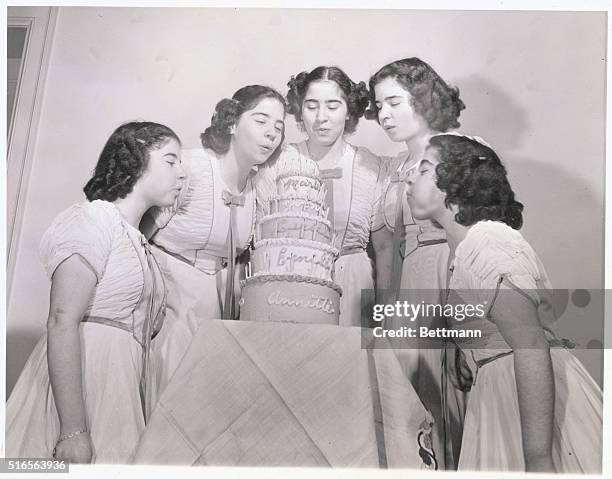 With the birthday celebration in full swing, the girls are shown blowing out the candles on the five-tiered, seventy-candled birthday cake. From left...