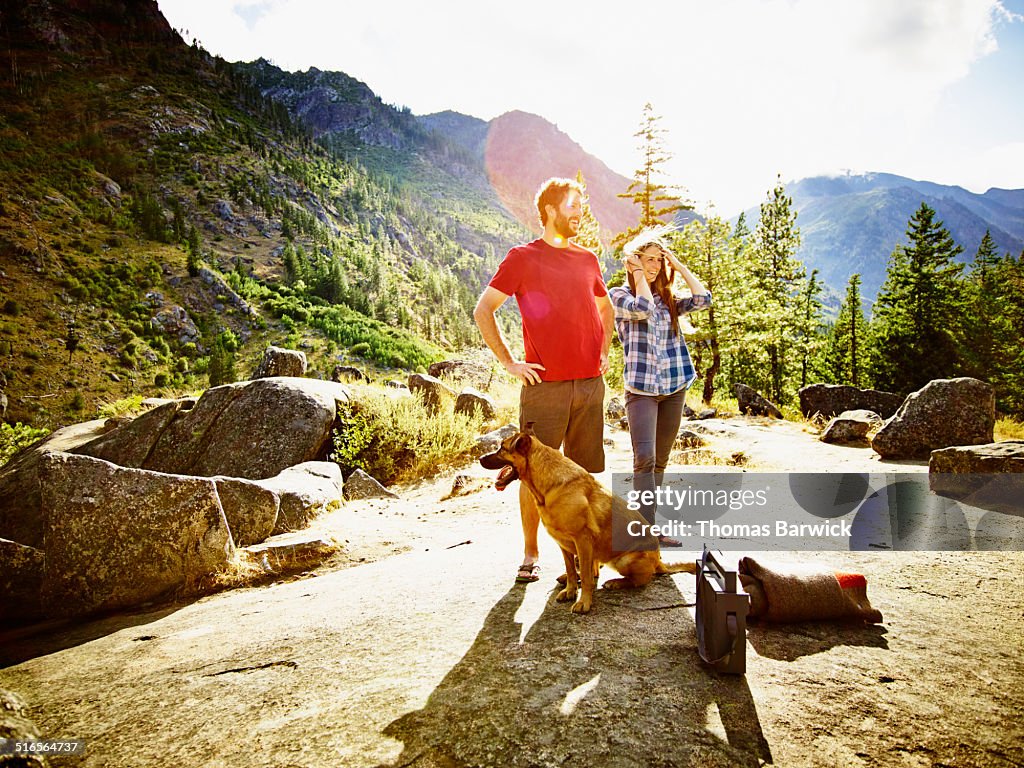 Smiling couple standing at overlook with dog