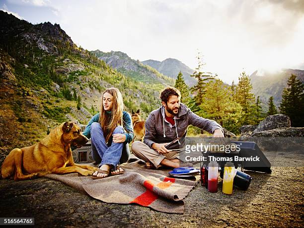 couple camping and barbecuing dinner at sunset - americas next top dog fotografías e imágenes de stock