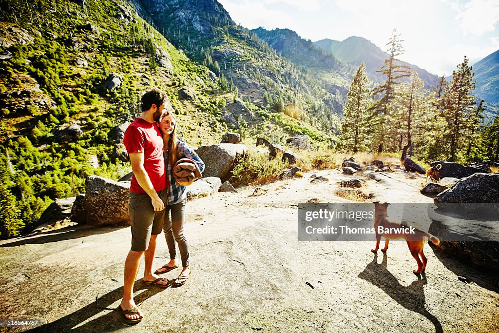 Smiling couple with dog standing at overlook