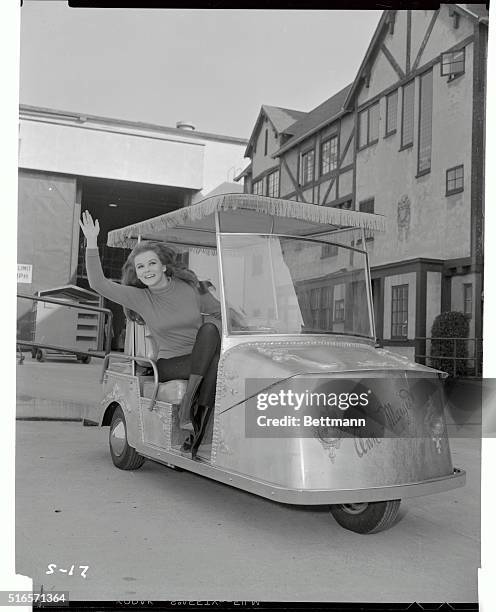 Ann-Margret, staring in "The Swinger", at Paramount Studios, waves from her new $7,000.00 gold golf cart that she uses for transportation around the...