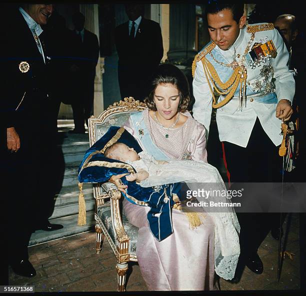 Athens, Greece....King Constantine bends down to assist his wife, the lovely Queen Anne-Marie who is holding the couple's first child, Crown Princess...