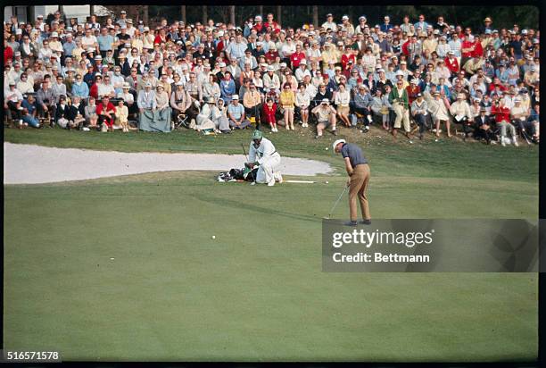 Don January blasts out of a sand trap and lines up his putt on the 18th hole during third round of the Masters Golf Tournament April 9.