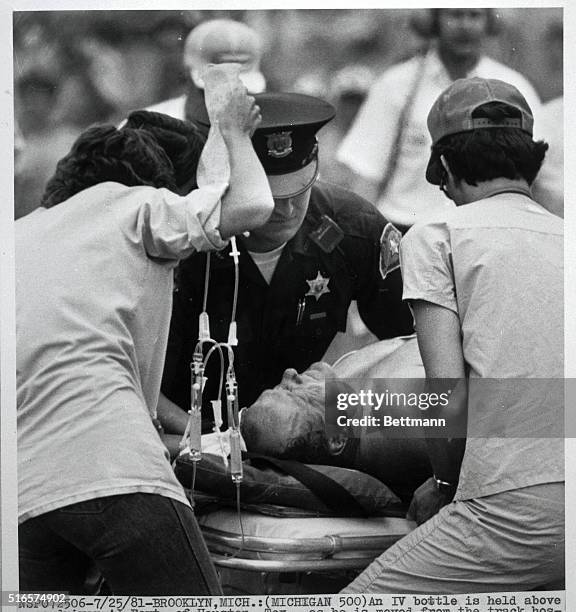 An IV bottle is held above race car driver A.J. Foyt, of Houston, Texas, as he is moved from the track hospital to a helicopter that took him to...