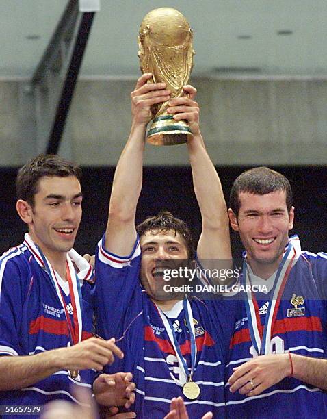 French forward Robert Pires is flanked by defender Bixente Lizarazu and midfielder Zinedine Zidane as he holds the FIFA trophy 12 July at the Stade...