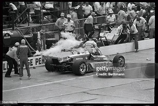 Rick Mears jumps from his car as it is enveloped in white-hot flames in the pits during the Indy 500. Mear's wife, Dina Lynn is held back by crew...