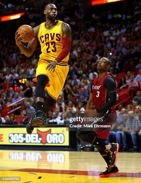 LeBron James of the Cleveland Cavaliers dunks over Dwyane Wade of the Miami Heat during a game at American Airlines Arena on March 19, 2016 in Miami,...