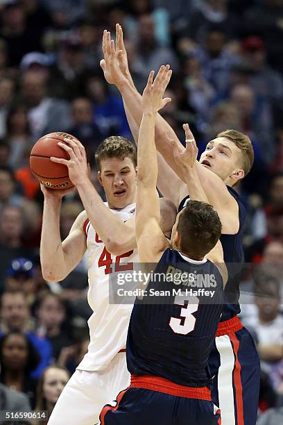Jakob Poeltl of the Utah Utes is defended by Kyle Dranginis and Domantas Sabonis of the Gonzaga Bulldogs in the second half during the second round...