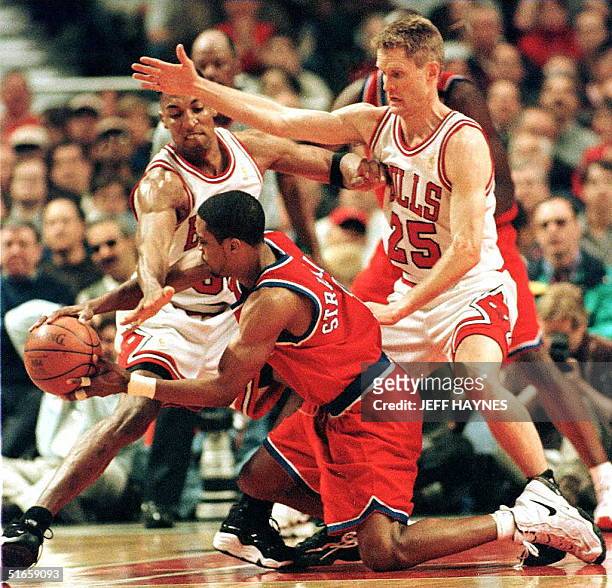 Rod Strickland of the Washington Bullets falls in front of Scottie Pippen and Steve Kerr of the Chicago Bulls 27 April during the first half of game...