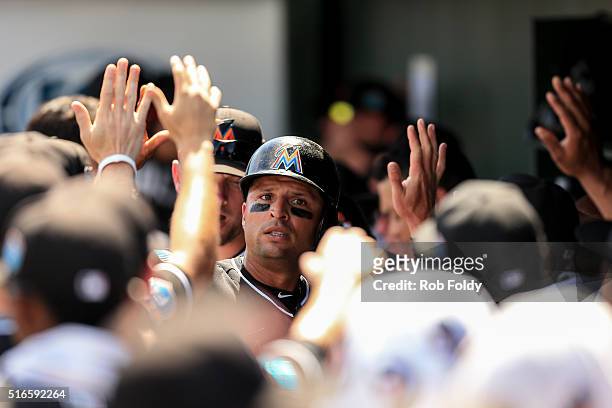 Martin Prado of the Miami Marlins high-fives teammates after scoring on an RBI single hit by Ichiro Suzuki during the spring training game against...