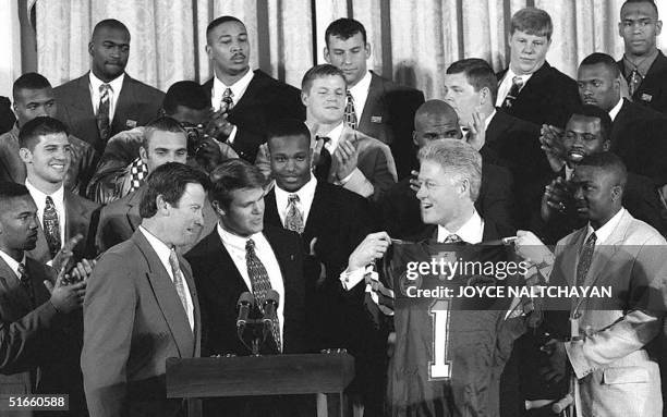 President Bill Clinton is holds a University of Florida Gators team jersey presented to him by the Gators' coach, Steven Spurrier and quarterback...