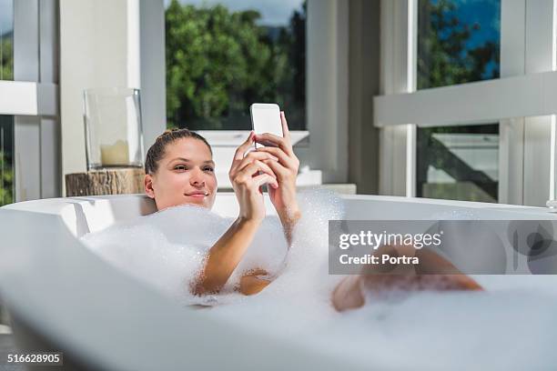 beautiful woman using smart phone in bathtub - beautiful woman bath photos et images de collection