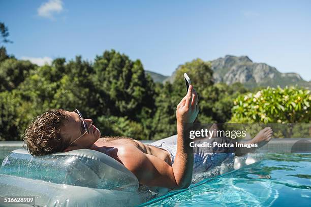 man using mobile phone on pool raft - pool raft imagens e fotografias de stock