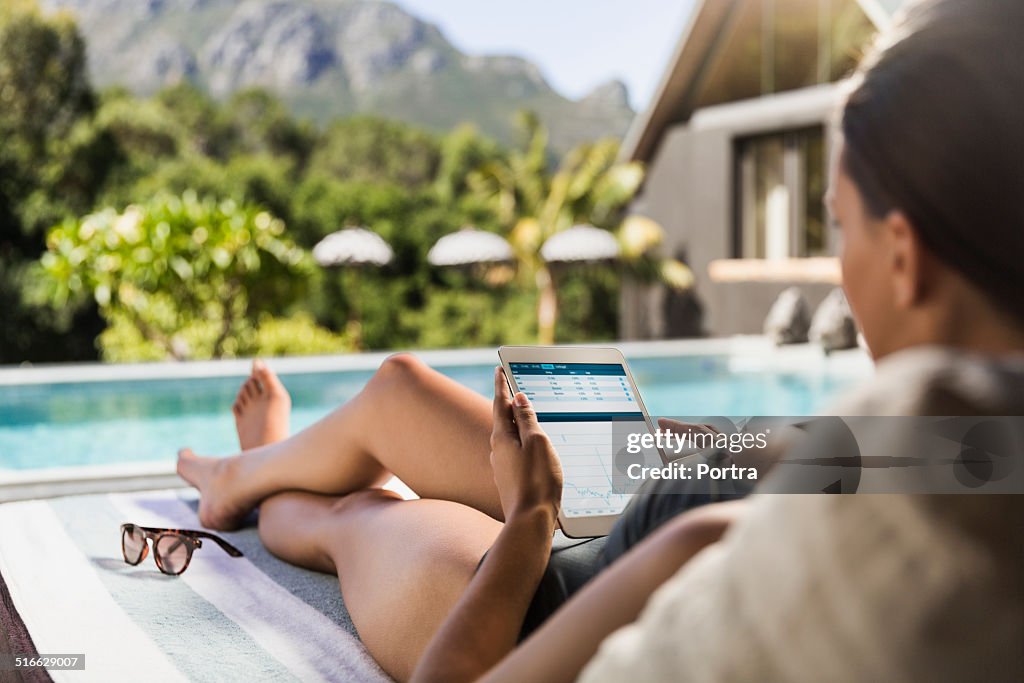 Woman using digital tablet at poolside