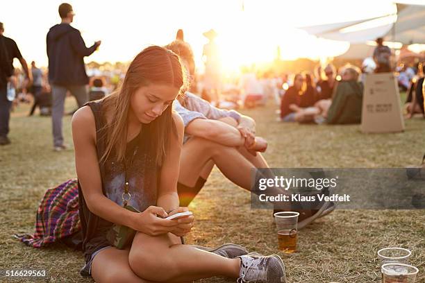 young woman tjecking smartphone at festival - festival stockfoto's en -beelden
