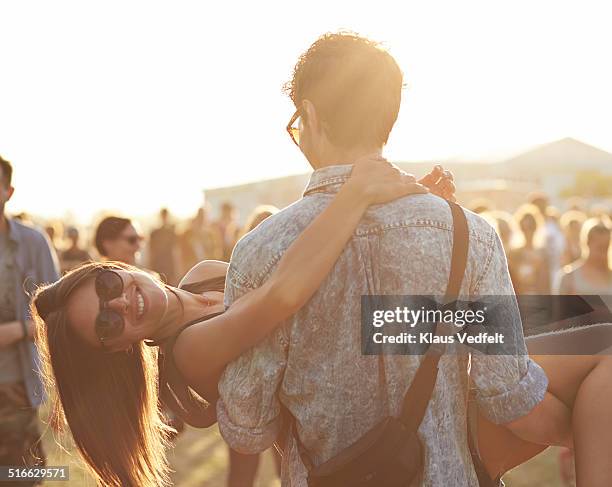 girl getting carried by boyfrend at festival - gentleman stock-fotos und bilder