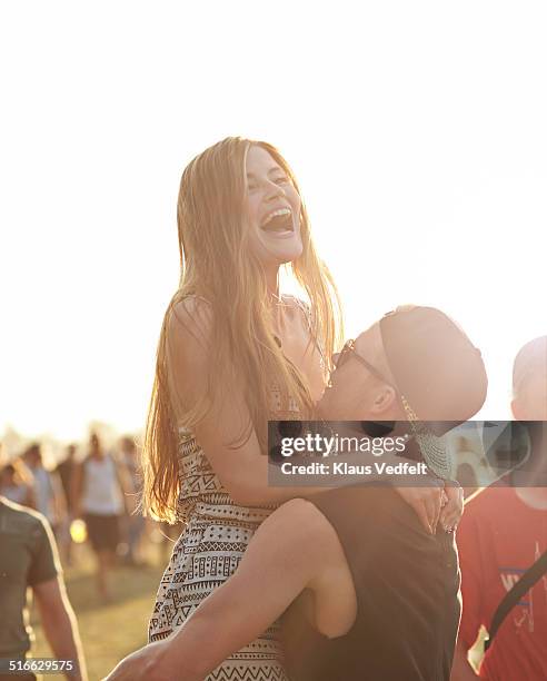 guy lifting up girlfriend at outside festival - couple concert photos et images de collection