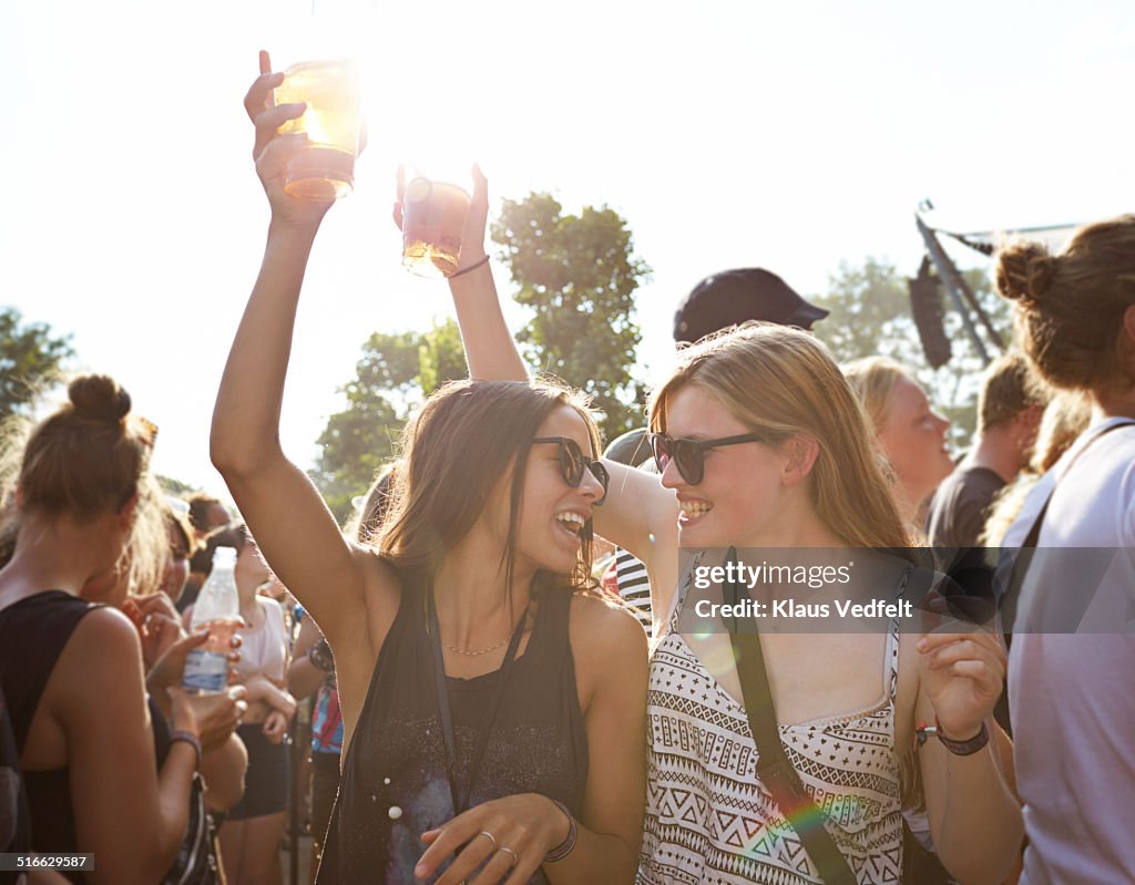 Girlfriends cheering with beer at concert outside