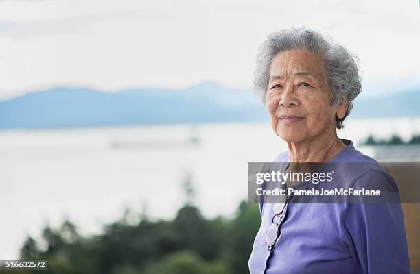 independent senior asian woman enjoying view from apartment, vancouver, canada - chinese people posing for camera stock pictures, royalty-free photos & images