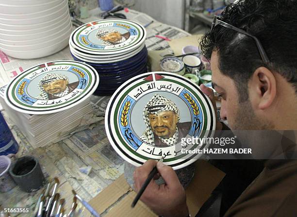 Palestinian painter paints on ceramic plates the portrait of Palestinian leader Yasser Arafat in the West Bank city of Hebron 04 November 2004....