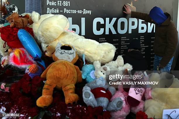 Man mourns by a tribute banner to the victims of an aircrash at the Rostov-on-Don airport entrance on March 20, 2016. The banner reads : "We mourn"....